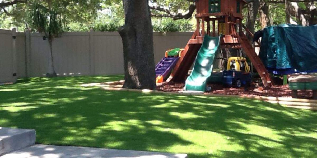Backyard play set on new synthetic turf under an oak