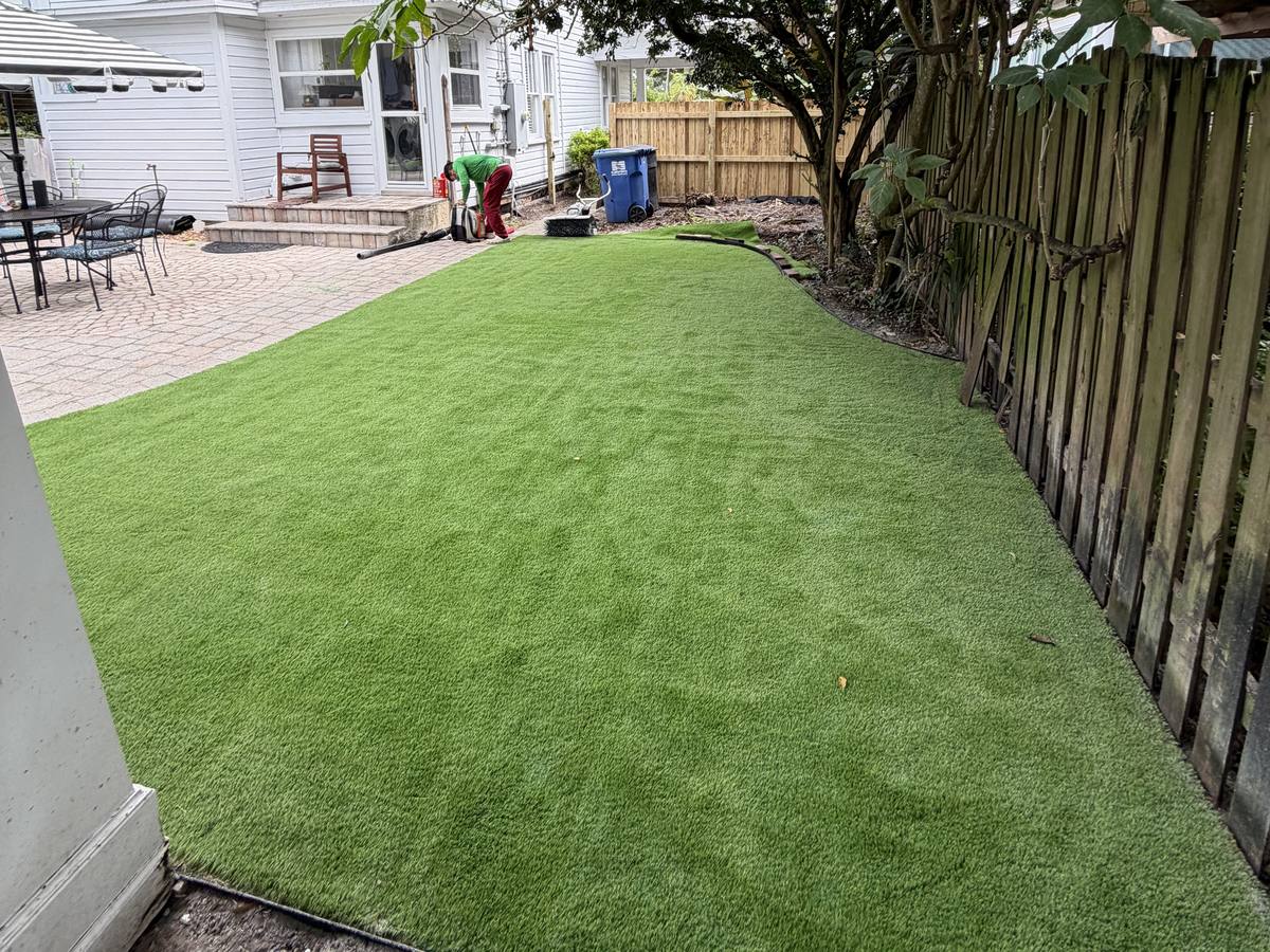 Pet turf running along a wood privacy fence under a large tree
