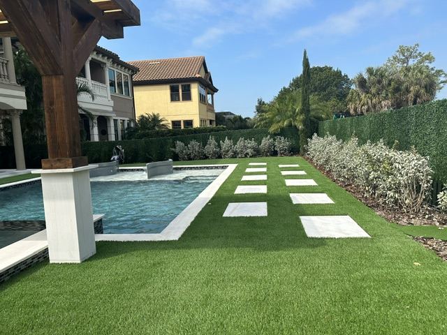 Synthetic turf lawn around a rectangular pool with square stepping pavers